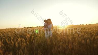 一个快乐的妈妈在日落时带着一个小女儿在一片麦田里抱着她。 宝贝和她妈妈<strong>一起走过</strong>